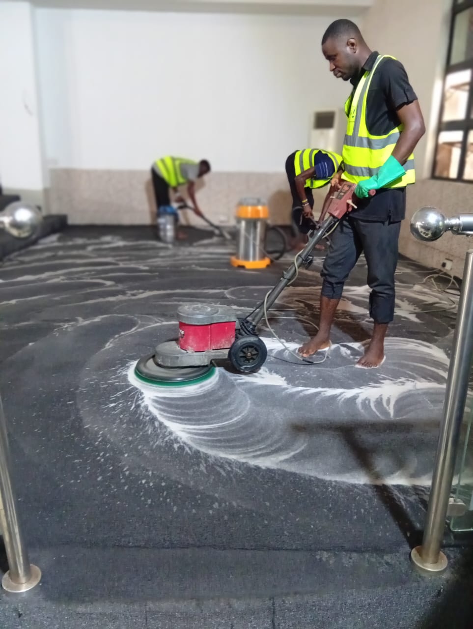 Industrial carpet shampoo machine deep cleaning a black office carpet